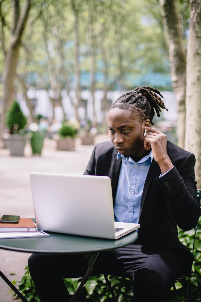 Young man in suit working on laptop outdoors, focused and professional.